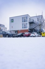 Modern buildings with snowy parking lot full of cars in winter, Gechingen, Calw district, Germany