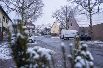 Snowy village road with parked cars and traditional ensemble of houses, Gechingen, Calw district,