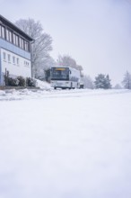 Snowy road with a bus and buildings in the background, cloudy, Gechingen, Calw district, Germany
