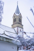 Snowy church tower with gothic elements and surrounding trees in winter, Gechingen, Calw district,