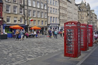 Red telephone boxes on a busy street in front of old buildings, Royal Mile, Edinburgh, Scotland,