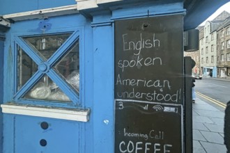 A blue-painted kiosk with a sign advertising English language skills, Humor, Royal Mile, Edinburgh,
