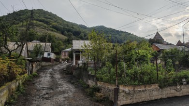 A rural village with green hills and a quiet village road, atmospheric village, Armenia