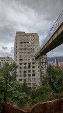 An old prefabricated building connected by a bridge with a grey sky, interesting building from a