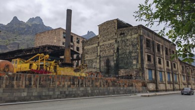 Abandoned industrial plant, factory with chimney and mountains in the background, Armenia