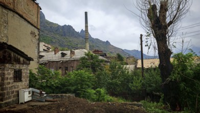 Old factory, ruins of buildings surrounded by mountains and dense vegetation, Armenia