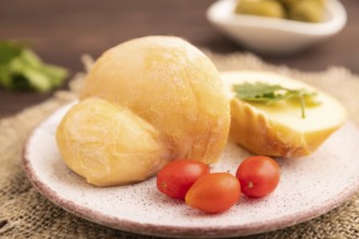 Smoked Mozzarella cheese, with tomatoes and olives on brown wooden background and linen textile,