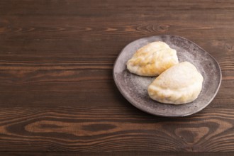 Glazed Pies with Cowberry jam in gray plate on brown wooden background, side view, copy space