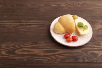 Smoked Mozzarella cheese, with tomatoes and olives on brown wooden background, side view, copy