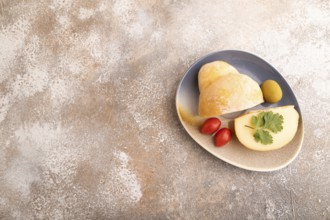 Smoked Mozzarella cheese, with tomatoes and olives on brown concrete background, top view, flat