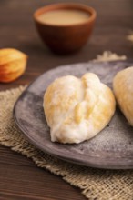 Glazed Pies with Cowberry jam on brown wooden background and linen textile, cup of coffee, side