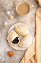 Glazed Pies with blueberry jam on brown concrete background and orange linen textile, cup of