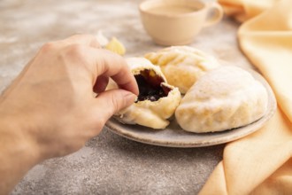 Glazed Pies with blueberry jam on brown concrete background and orange linen textile with hand, cup