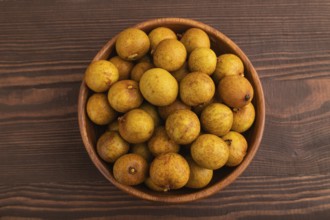 Ripe Longan in wooden bowl on brown wooden background, Top view, flat lay, close up, minimalism