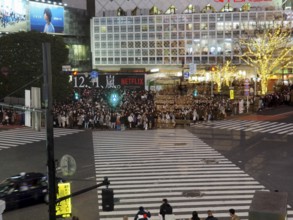 Crowds of people at night at a busy urban crossroads, Shibuya, Tokyo, Japan