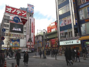 Busy street intersection in a Japanese city with tall buildings and colorful billboards, Akihabara