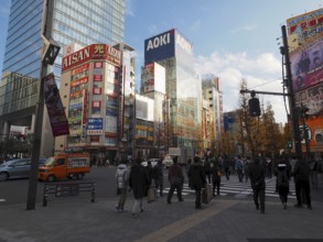 People cross a busy city street surrounded by modern buildings and commercials, Akihabara Electric