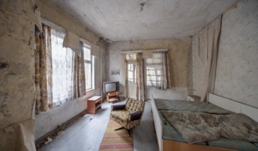 Abandoned hotel room with bed, armchair and television in a dilapidated hotel, Lost Place,