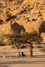 Secluded campground with a tree in the desert of Spitzkoppe, surrounded by large rock formations,