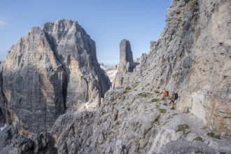 Climbers on a rock band, Bocchette Centrale band trail, via ferrata in the Brenta Mountains,