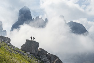 Alpine panorama, mountaineers on a large rock, fog and Torre Di Brentai and Cima Tosa, rocky