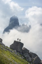 Alpine panorama, mountaineers on a large rock, fog and Torre Di Brentai and Cima Tosa, rocky