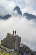 Mountaineers on a large rock, fog and Torre Di Brentai, rocky mountain peaks and mountain