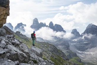 Female mountaineer looking at fog and Torre Di Brentai, rocky mountain peaks and mountain