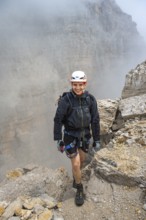 Happy mountaineer, Via Ferrata Oliva Detassis via ferrata in fog, rocky mountain peaks and mountain