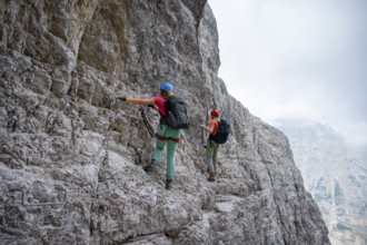 Two mountaineers climbing on rock face, rocky mountain landscape, Via Ferrata SOSAT via ferrata,