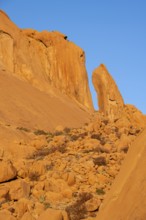 Large, sun-lit rock formations against a clear sky in the desert landscape of Spitzkoppe,