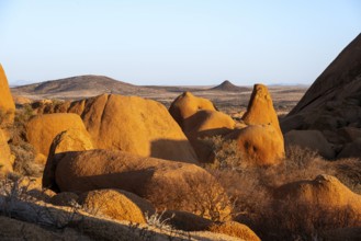 Rocks cast shadows over the dry landscape that stretches in the distance in the Spitzkoppe Desert,