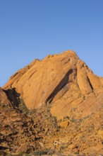 Hilly rock formation rising against the blue sky in the dry desert, Spitzkoppe, Namibia