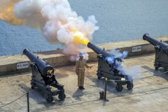 Soldier firing cannon salute with SBBL 32-pounder gun at 16th century Saluting Battery at Grand