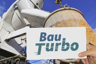 (photo montage) Sign with the BAUTURBO logo in front of a truck unloading ready-mix concrete