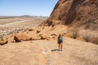 Female hiker explores an impressive rocky landscape in the Namibian desert, Spitzkoppe, Namibia