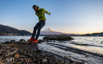 Young man jumping, Lake Kawaguchi, view of Mount Fuji volcano at sunset, Yamanashi Prefecture,