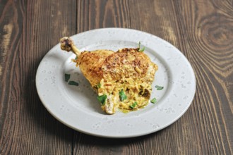 A chicken leg cooked and placed on a round plate. The dish features a creamy mushroom sauce and is