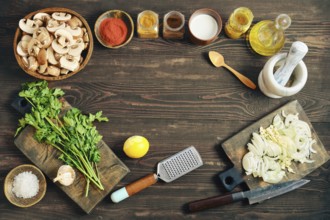 Fresh ingredients and tools for cooking are arranged on a wooden tabletop. Flat lay with chopped