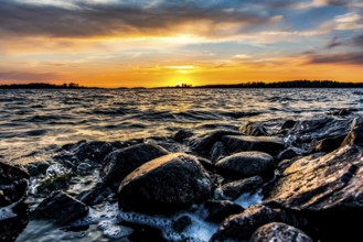 A colorful sunset over Lake Vänern with waves hitting dark rocks, Värmlands Näs, Värmlands län,