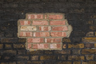 Partially repaired brick wall with contrast of old and new stones, London, England, Great Britain