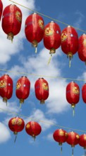 Red Chinese lanterns hanging on yellow lines against a blue sky, London, England, Great Britain