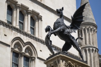 Metal statue of a winged dragon in front of the neo-Gothic building of the Royal Court of Justice,