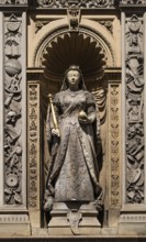 Queen statue with scepter and orb surrounded by decorative elements depicting Queen Victoria,