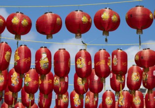 Red Chinese lanterns hanging on yellow lines against a blue sky, London, England, Great Britain