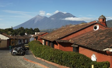 Traditional houses in a cobblestone alley with the Fuego volcano in the back, Old Town, Antigua,