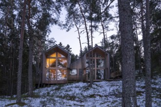 Internally illuminated modern wooden house in a wintery forest, cozy atmosphere, Korpoström, Korpo