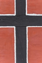 Close-up of a timber-frame structure with red background and black bars, nave, reconstructed
