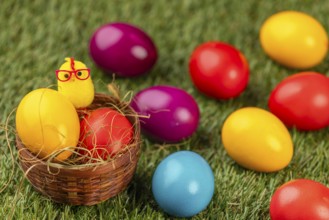 Colourful easter eggs and a chick figure on green grass