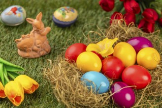 Colourful easter eggs and an Easter bunny with spring flowers on grass